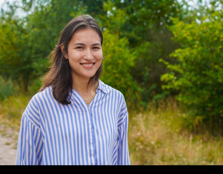 Een vrouw loopt in de natuur. Je ziet haar vanaf haar bovenlijf.
