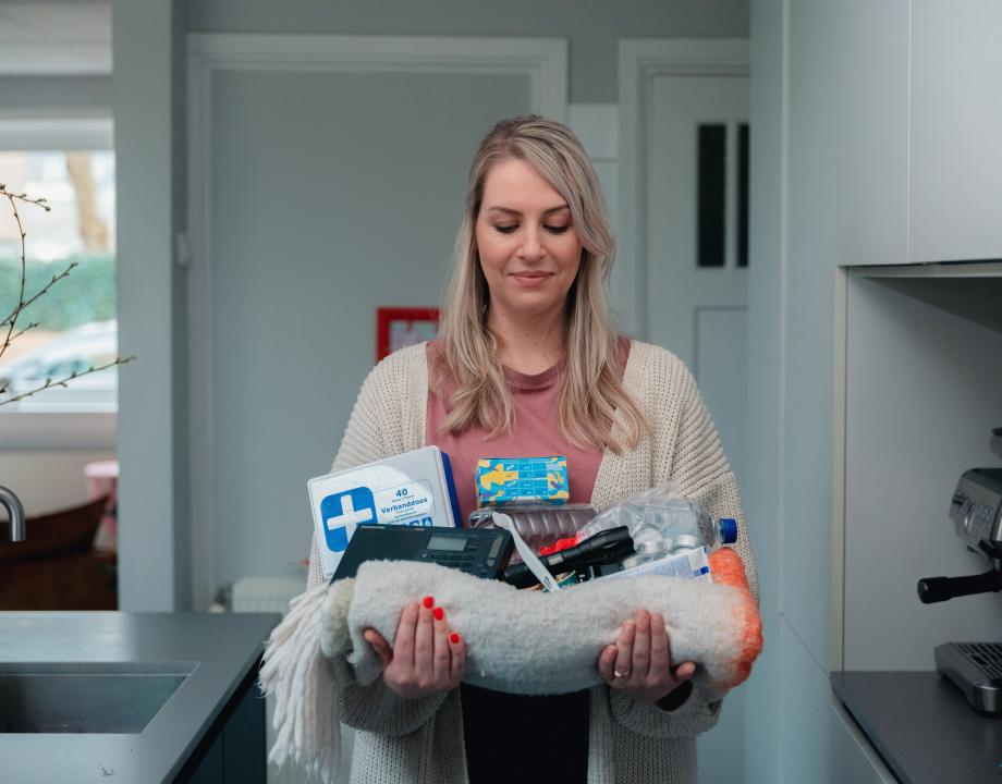 Vrouw met producten in haar hand die bij een noodpakket horen
