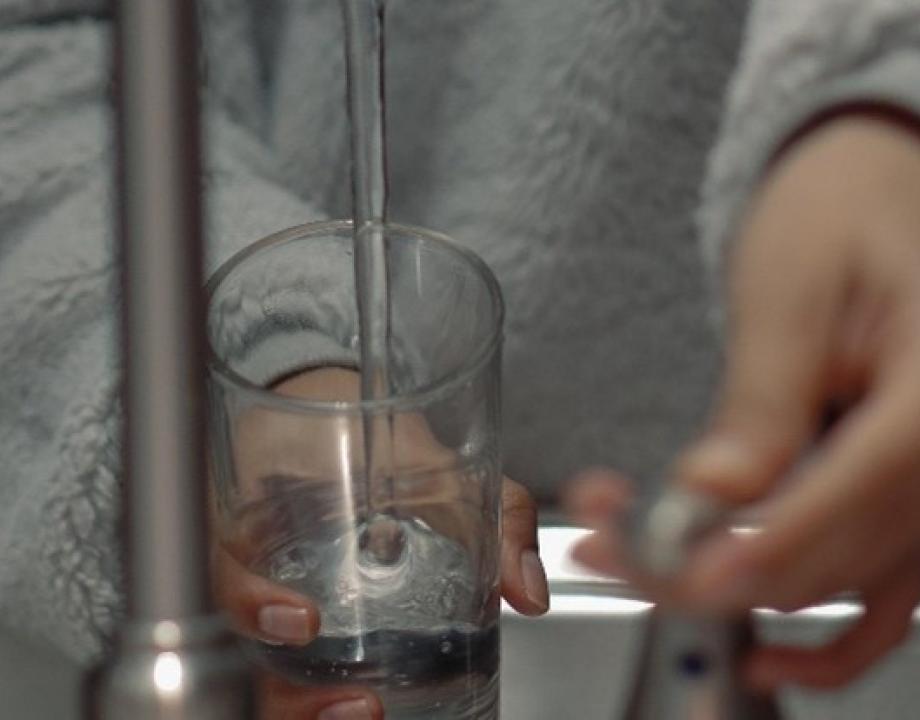 Vrouw met glas in haar hand pakt water uit de kraan