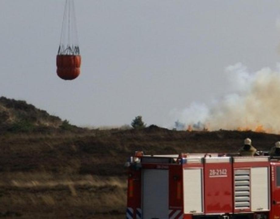 Chinook helikopter van defensie met een waterzak eronder om een brand te blussen