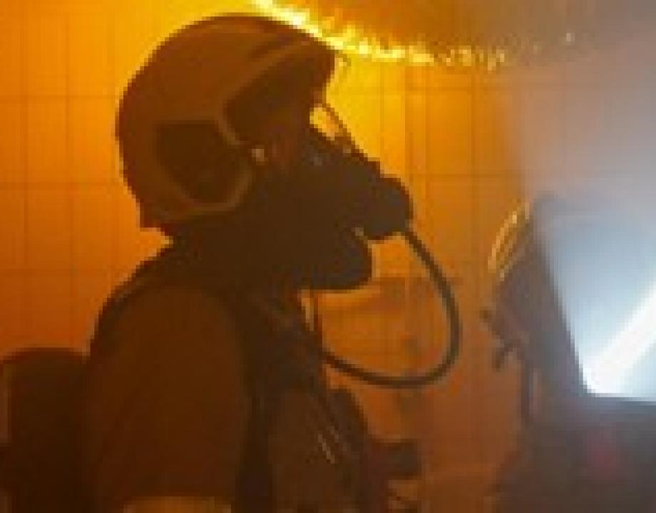 Brandweerman met zuurstofmasker in een brandend pand