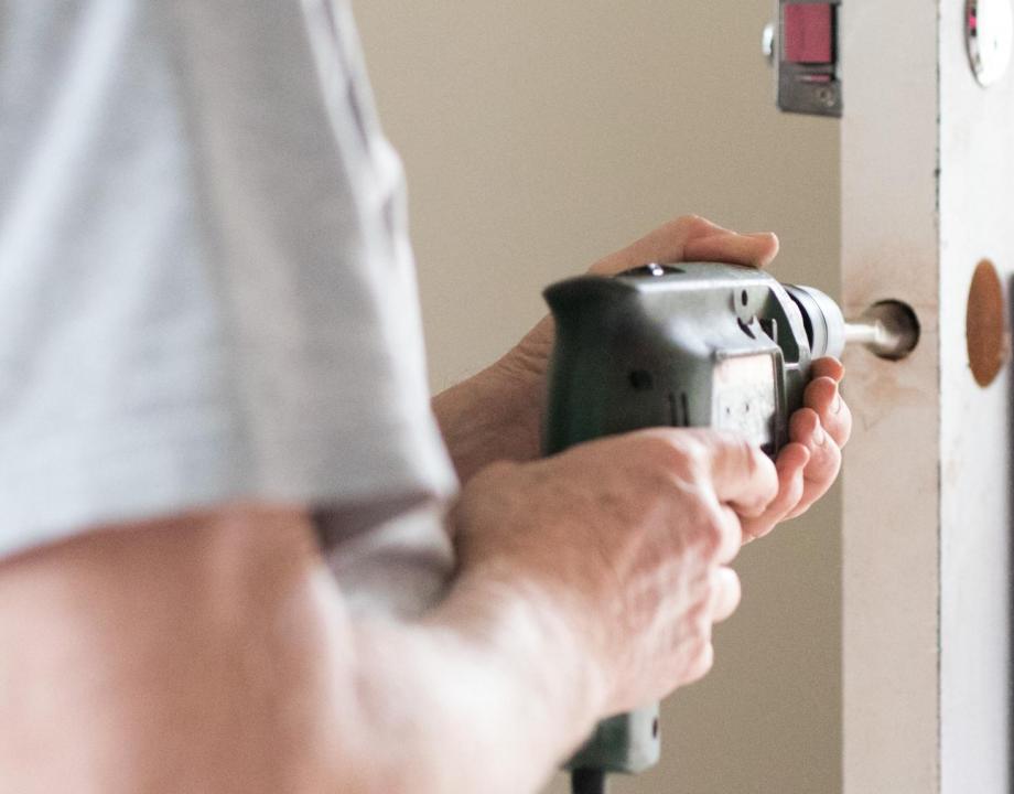 Man met boormachine in de hand is aan het klussen in een woning