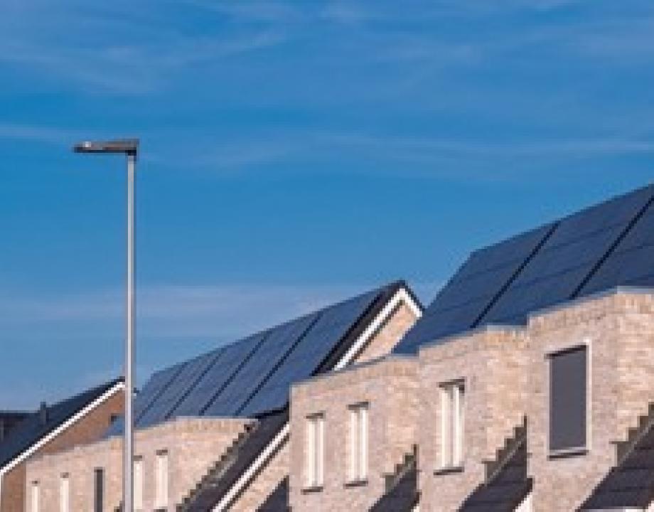 Dak van een rij woningen met zonnepanelen erop