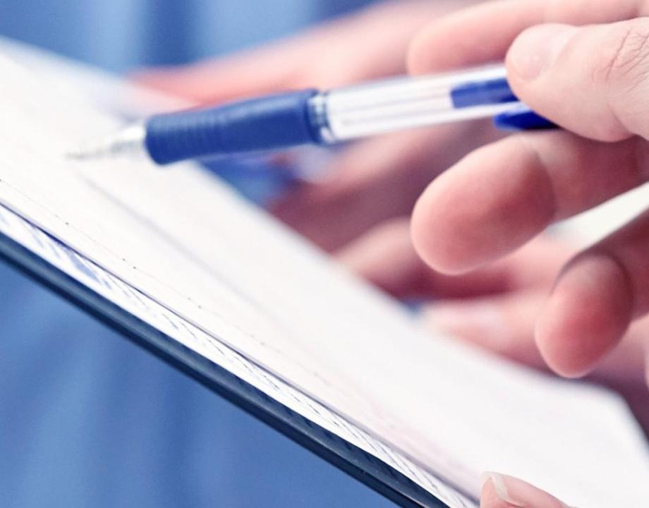 Hand van een arts die met een pen iets op een pagina aanwijst