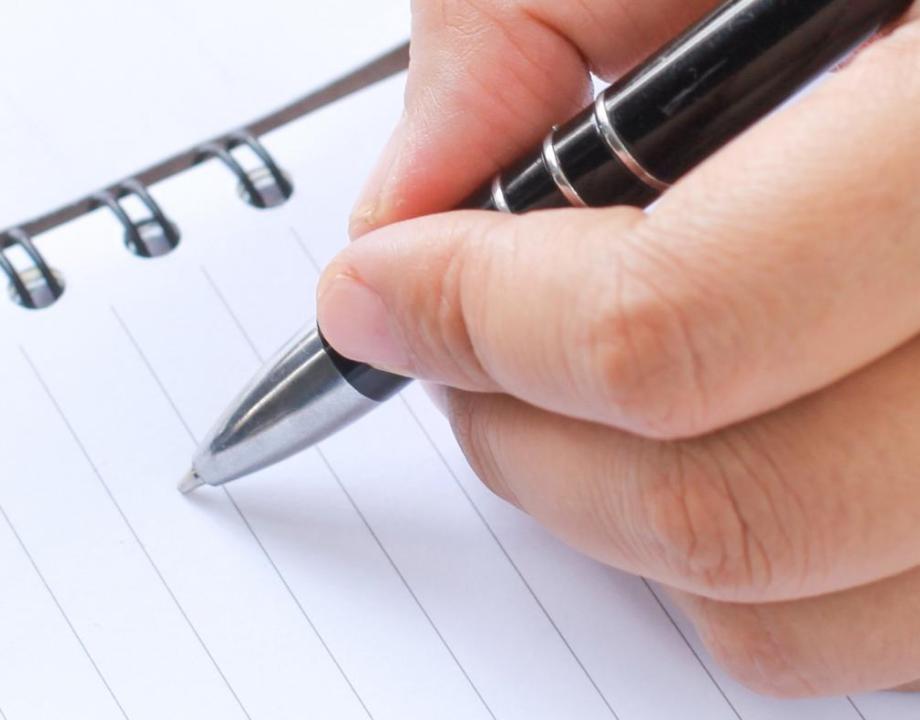 Hand die een pen vasthoud en in een notitieboekje wil gaan schrijven