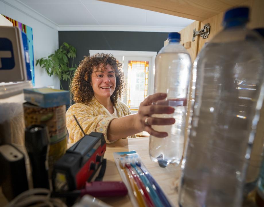 Vrouw pakt een fles water uit een voorraadkast