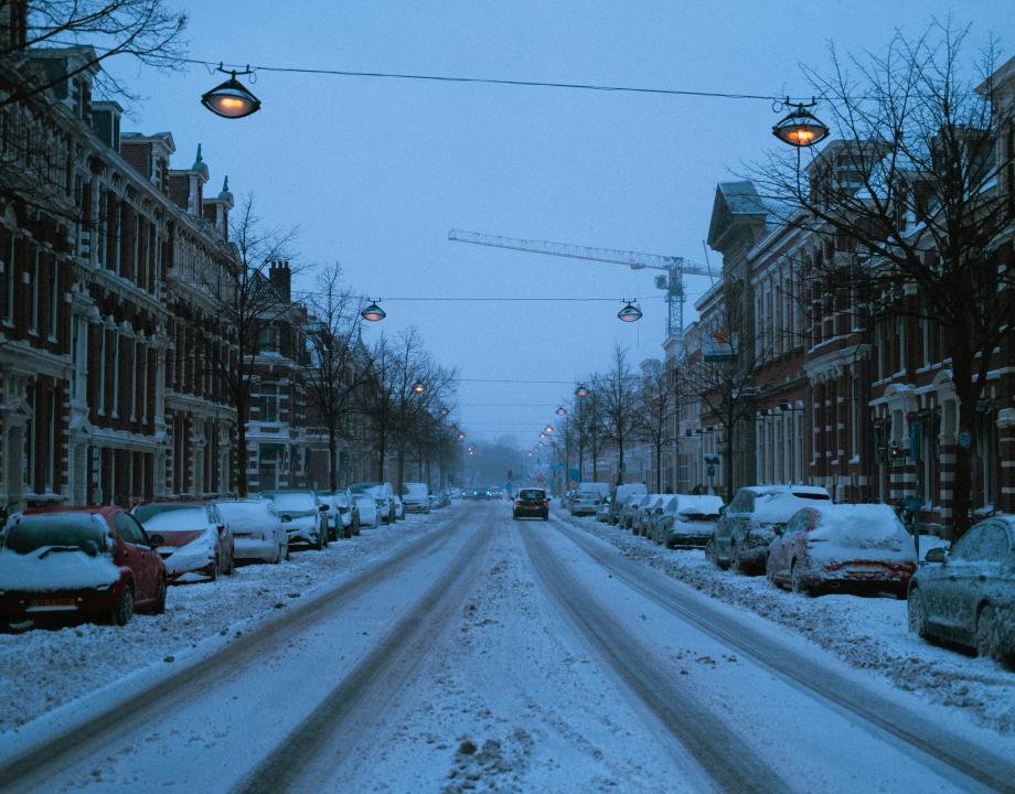 straat met sneeuw en geparkeerde auto's en huizen aan beide zijden