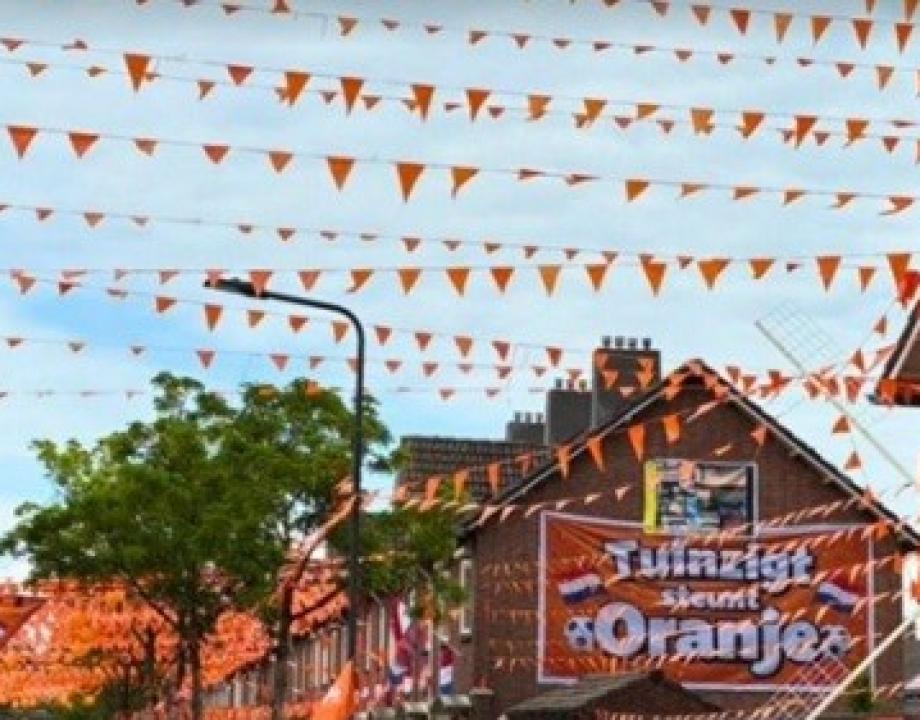 Straat met oranje vlaggetjes en spandoeken met teksten over het WK voetbal